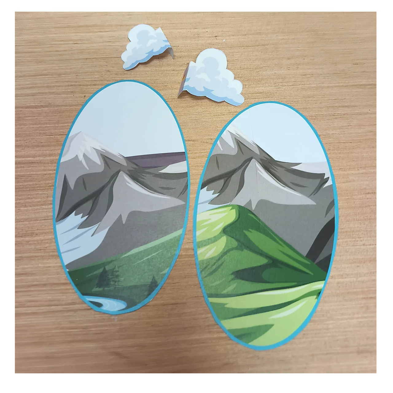 Dos ventanas ovaladas de papel y pequeñas nubes recortadas sobre la mesa