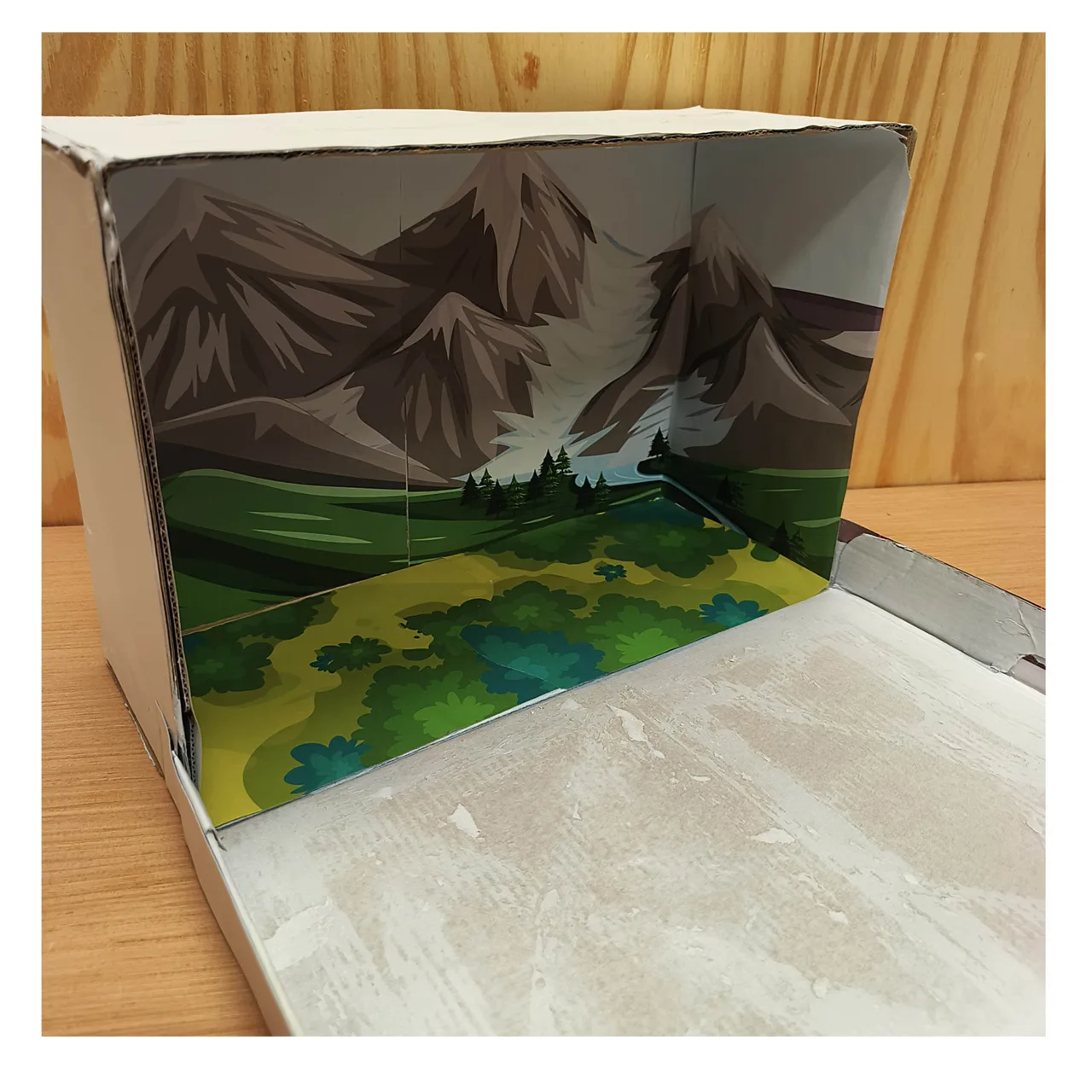 Suelo ilustrado colocado dentro de la caja bajo el paisaje de montañas