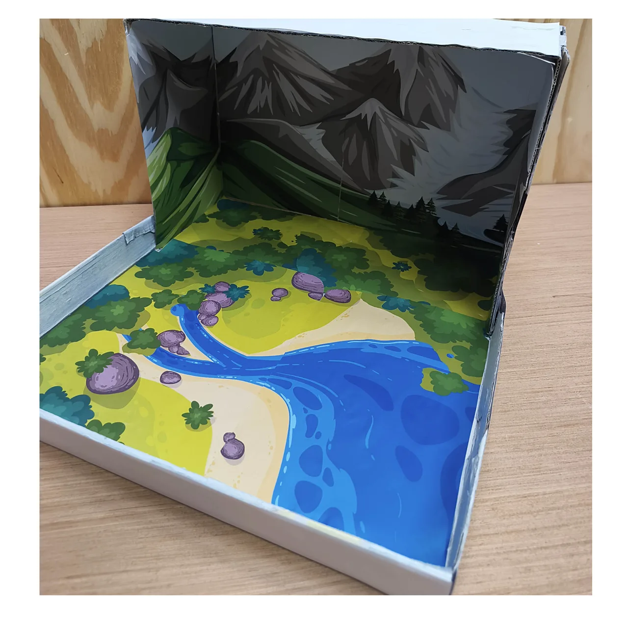 Paisaje con lago y vegetación extendido sobre la tapa abierta de la caja