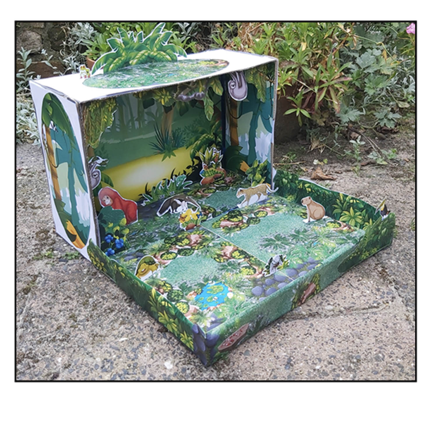 Maqueta de selva tropical 3D terminada dentro de una caja con animales y vegetación de papel