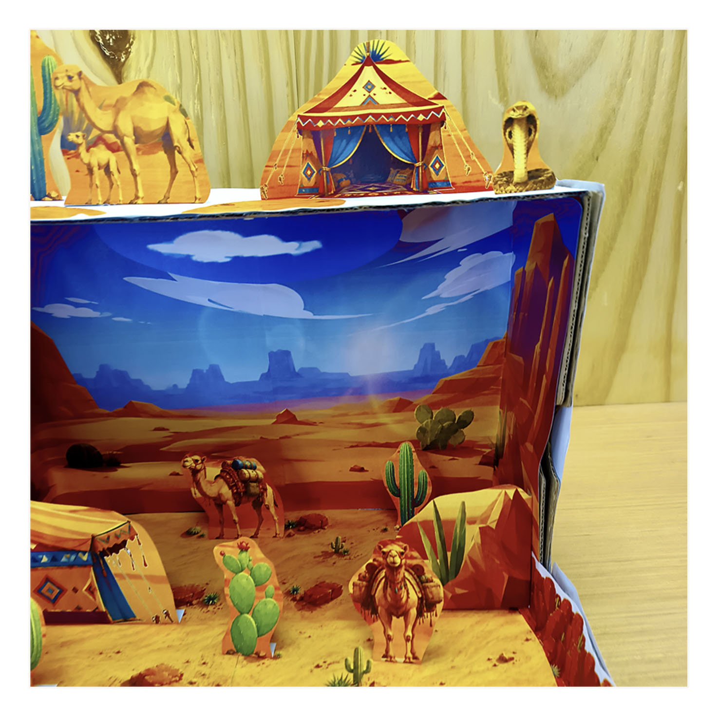 Maqueta del desierto 3D construida con camellos cactus y una tienda de papel